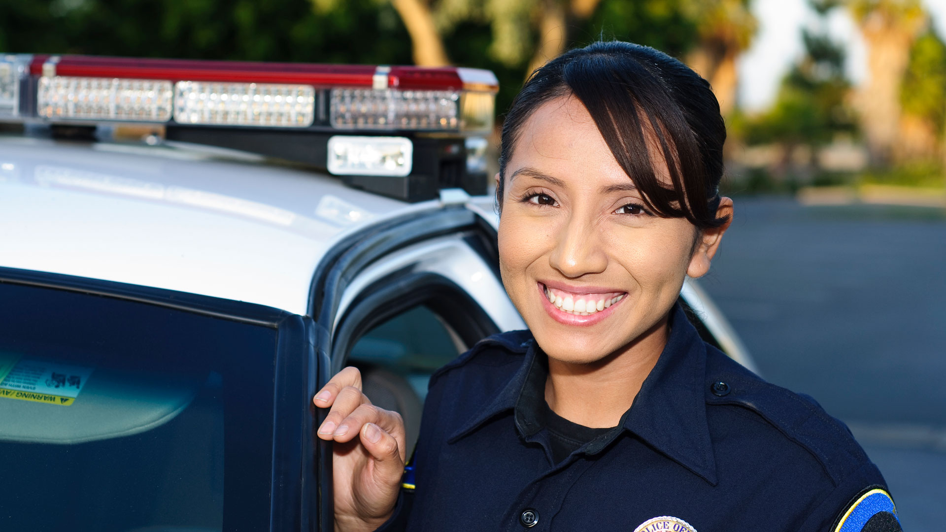 Female police officer smiling next to car